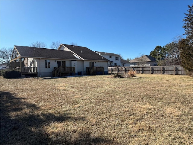 rear view of house featuring a wooden deck and a yard