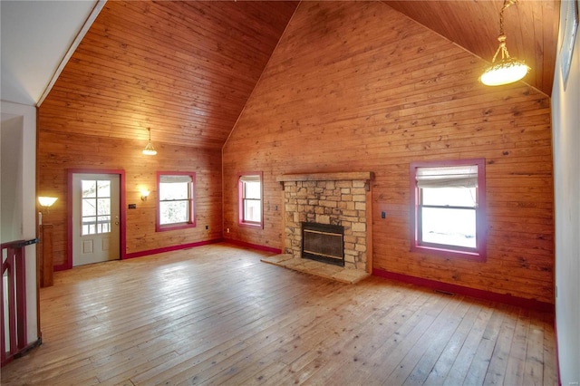 unfurnished living room featuring high vaulted ceiling, wood walls, light hardwood / wood-style floors, and a fireplace