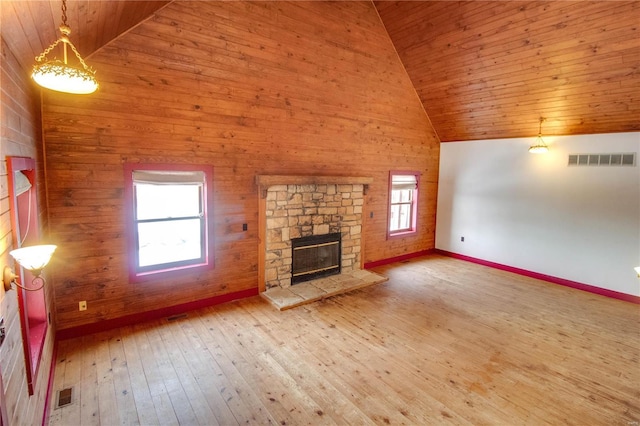 unfurnished living room with wooden ceiling, a healthy amount of sunlight, high vaulted ceiling, and a stone fireplace