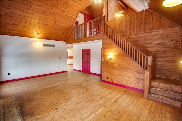 unfurnished living room with high vaulted ceiling, hardwood / wood-style flooring, wood ceiling, and wooden walls