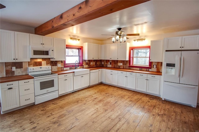 kitchen with beamed ceiling, white appliances, white cabinetry, sink, and light wood-type flooring