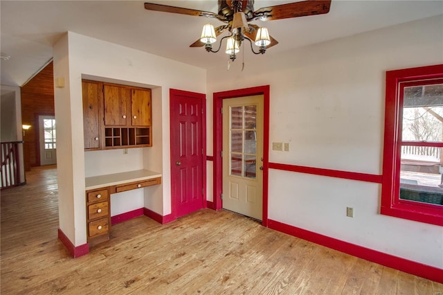 interior space with built in desk, a wealth of natural light, ceiling fan, and light hardwood / wood-style floors