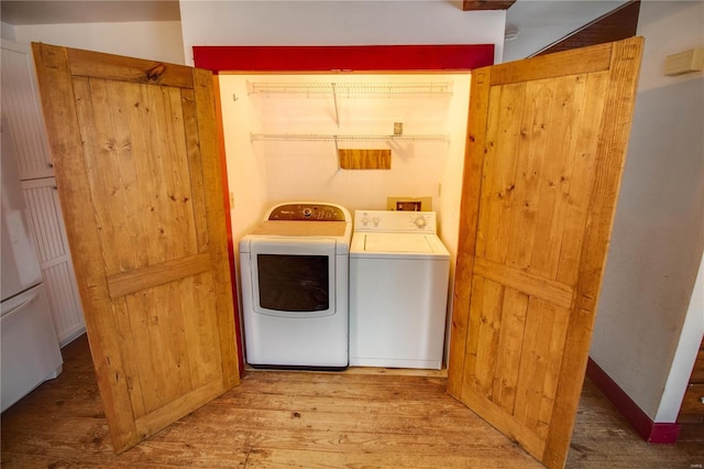 clothes washing area with hardwood / wood-style flooring and separate washer and dryer