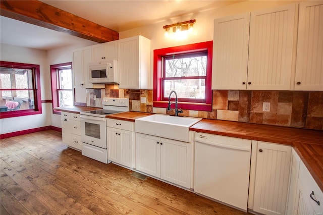 kitchen featuring white appliances, white cabinets, wood counters, sink, and beam ceiling