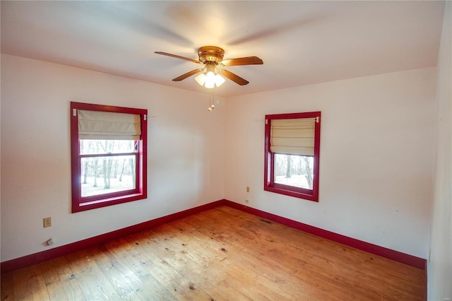 spare room with ceiling fan, wood-type flooring, and a healthy amount of sunlight