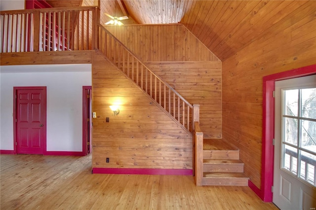 stairs featuring high vaulted ceiling, wooden ceiling, hardwood / wood-style floors, and wood walls