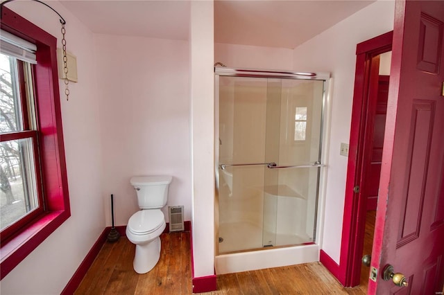 bathroom with wood-type flooring, toilet, and a shower with door