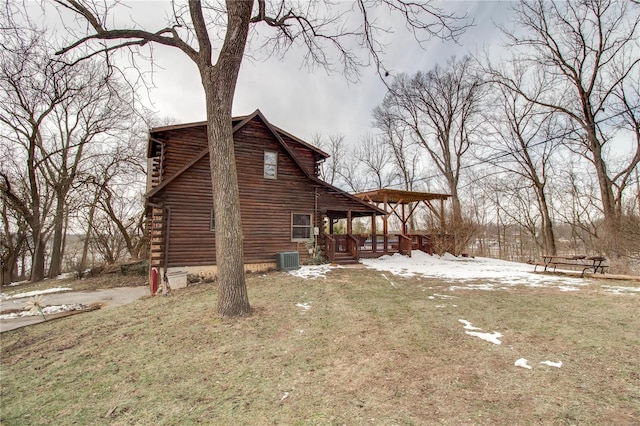 view of snow covered exterior with cooling unit, a porch, and a lawn