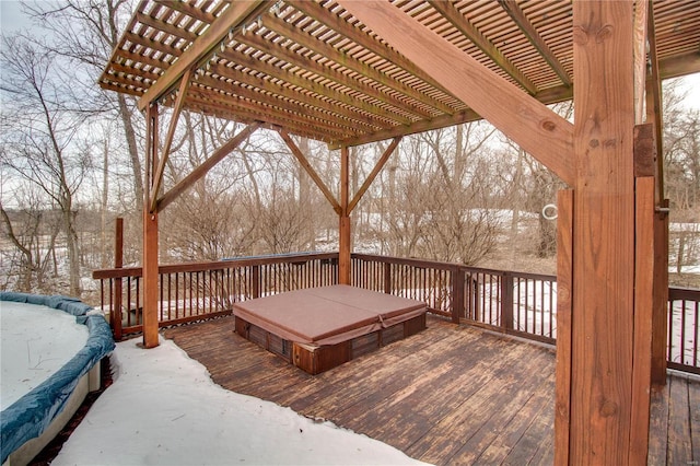 snow covered deck with a hot tub and a pergola