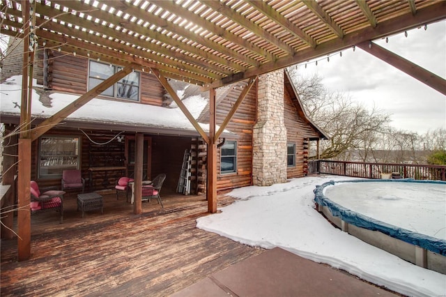 snow covered patio with a pergola and a wooden deck