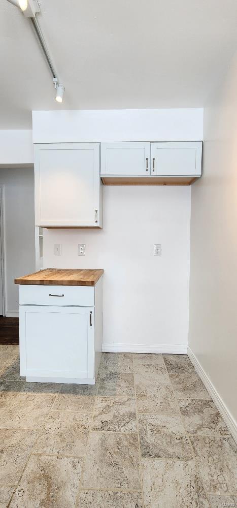 kitchen with white cabinetry, butcher block countertops, and track lighting