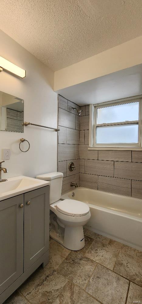 full bathroom featuring tiled shower / bath combo, toilet, a textured ceiling, and vanity