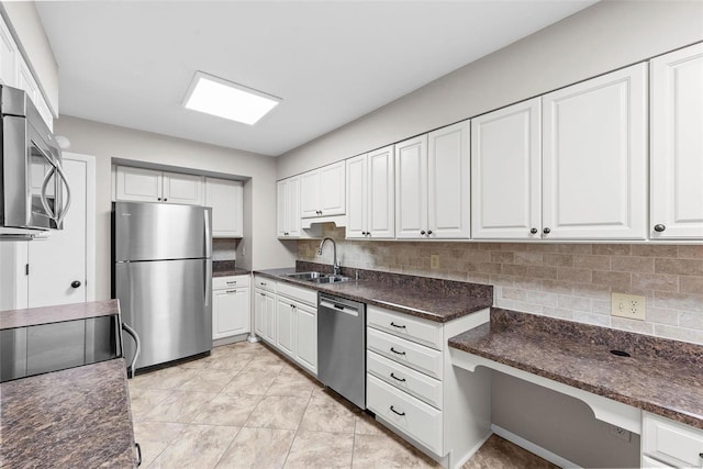 kitchen featuring sink, white cabinetry, built in desk, appliances with stainless steel finishes, and decorative backsplash