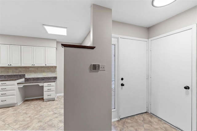 kitchen featuring white cabinetry, built in desk, and tasteful backsplash