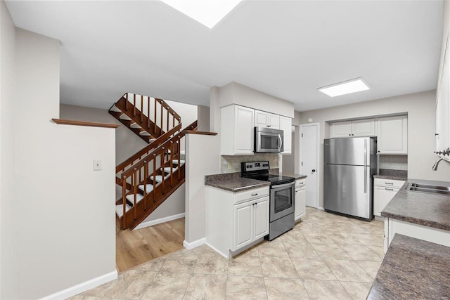 kitchen with sink, backsplash, white cabinets, and appliances with stainless steel finishes