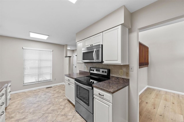 kitchen featuring stainless steel appliances, white cabinetry, and tasteful backsplash