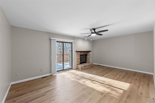 unfurnished living room featuring ceiling fan, a fireplace, and light hardwood / wood-style flooring