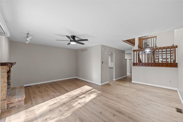 unfurnished living room featuring a fireplace, light hardwood / wood-style floors, and ceiling fan