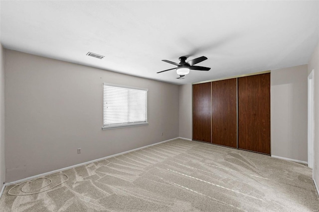 unfurnished bedroom featuring ceiling fan, light colored carpet, and a closet