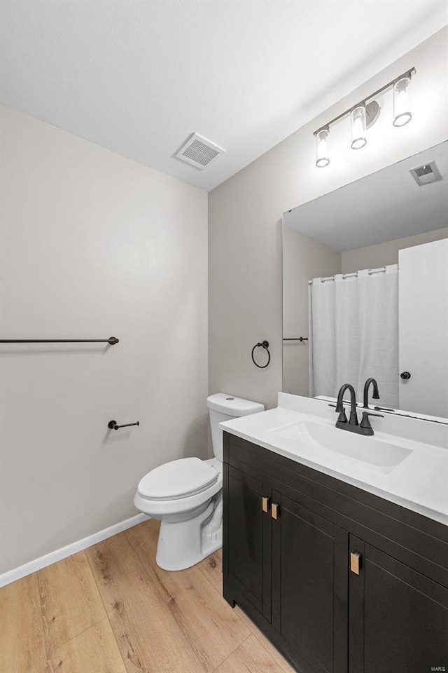 bathroom featuring a shower with curtain, wood-type flooring, vanity, and toilet