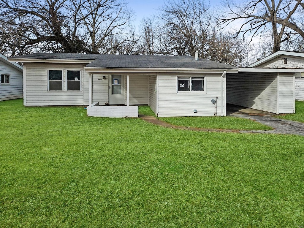 rear view of property featuring a carport and a yard