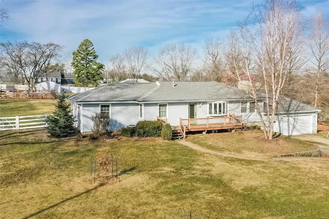 rear view of house with a wooden deck, a garage, and a lawn