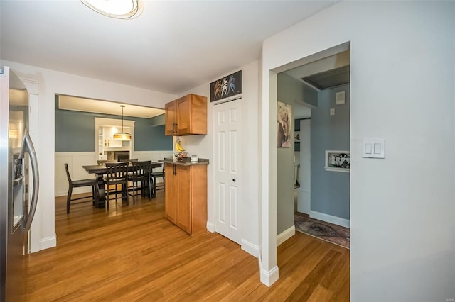 kitchen featuring decorative light fixtures, stainless steel fridge, kitchen peninsula, and wood-type flooring