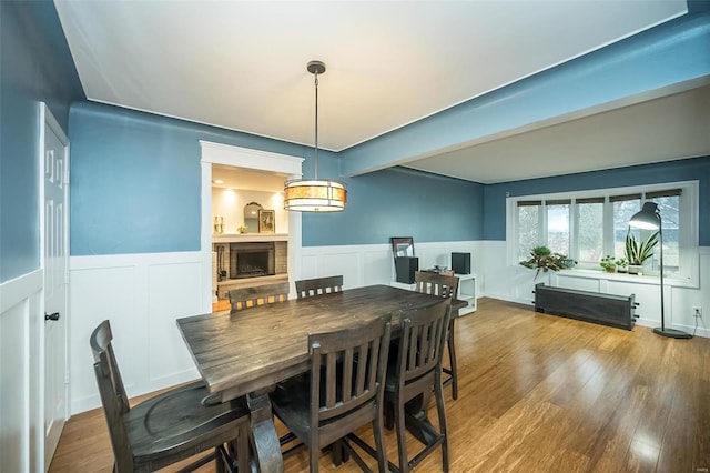 dining space featuring beamed ceiling, wood-type flooring, and a fireplace