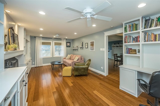 interior space with ceiling fan, built in desk, and light hardwood / wood-style floors