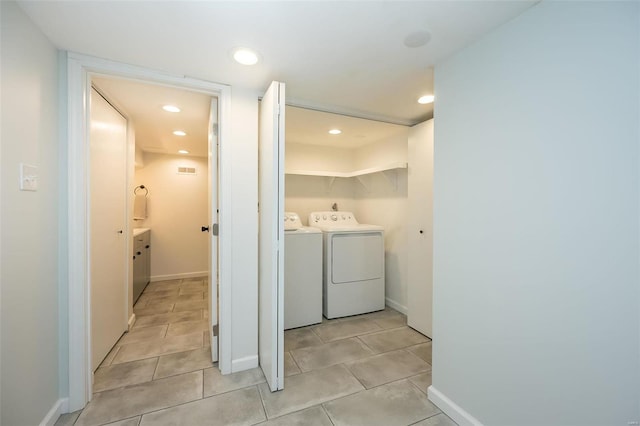 clothes washing area with washer and clothes dryer and light tile patterned floors