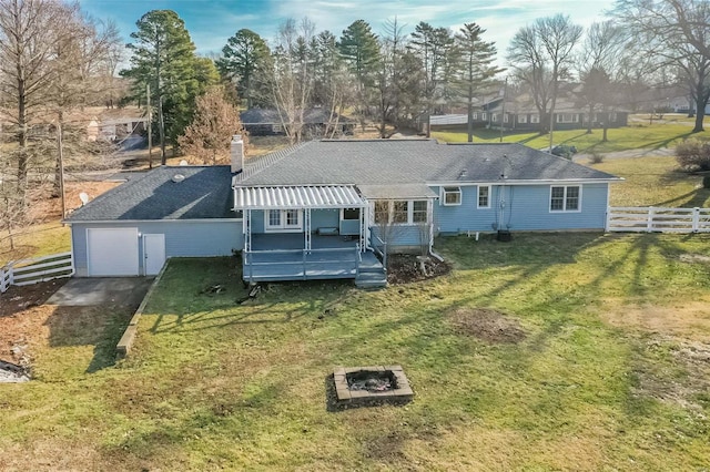 rear view of house with a garage, a fire pit, a lawn, and a deck