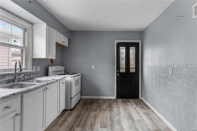 kitchen with white cabinetry, electric range, a wealth of natural light, and sink