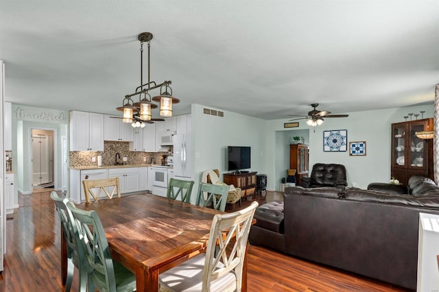 dining area with ceiling fan, sink, and dark hardwood / wood-style flooring