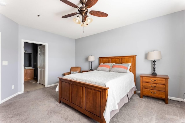 bedroom with ensuite bath, light colored carpet, and ceiling fan