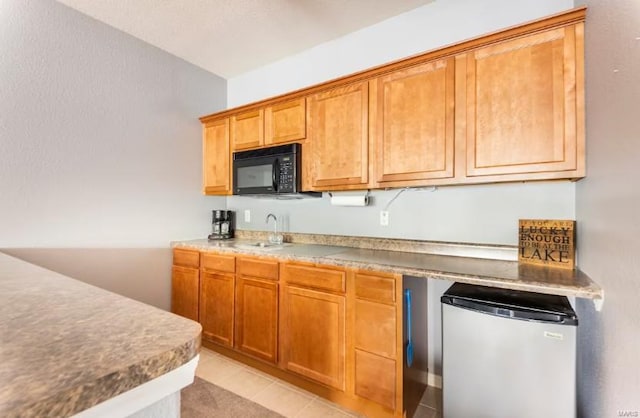 kitchen featuring light tile patterned flooring, stainless steel fridge, and sink