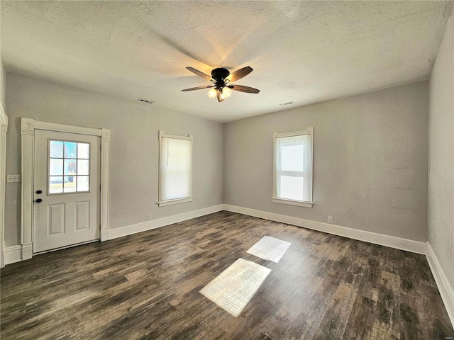 interior space with ceiling fan, plenty of natural light, dark hardwood / wood-style floors, and a textured ceiling