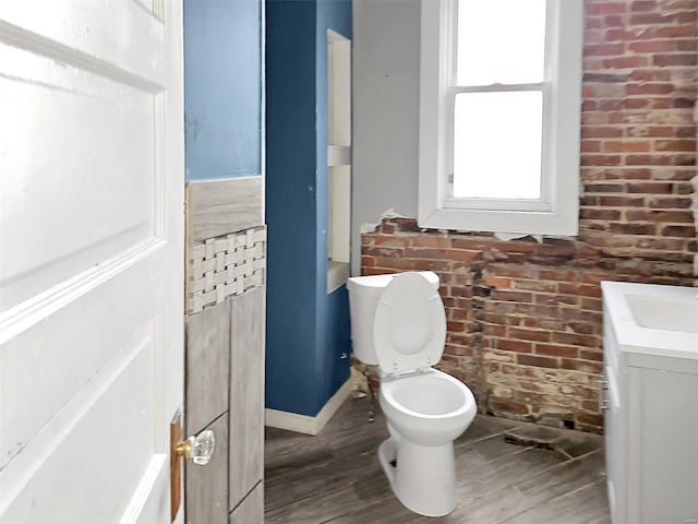 bathroom featuring brick wall, vanity, toilet, and hardwood / wood-style floors