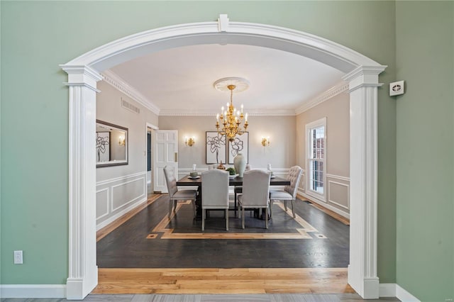 dining room featuring crown molding, dark wood-type flooring, a chandelier, and decorative columns