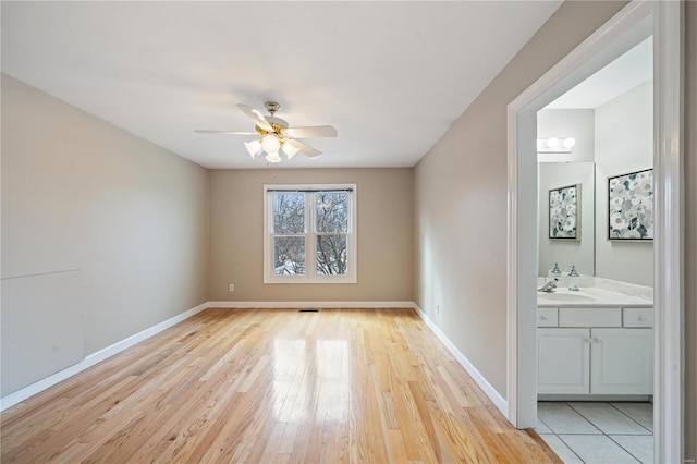 spare room featuring ceiling fan, sink, and light wood-type flooring