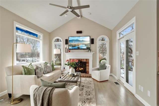 living room featuring hardwood / wood-style flooring, lofted ceiling, ceiling fan, and a brick fireplace