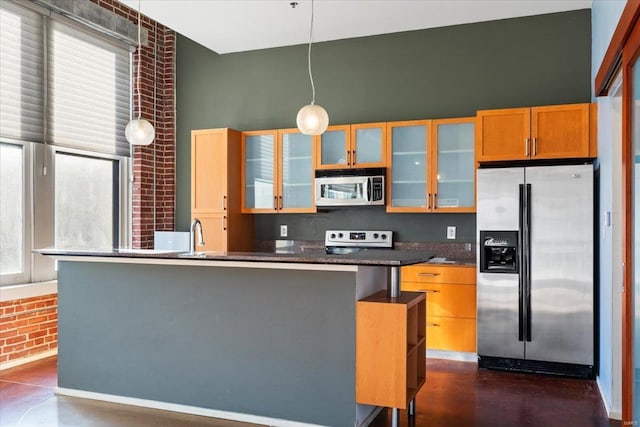 kitchen with stainless steel appliances, a breakfast bar, sink, decorative light fixtures, and brick wall