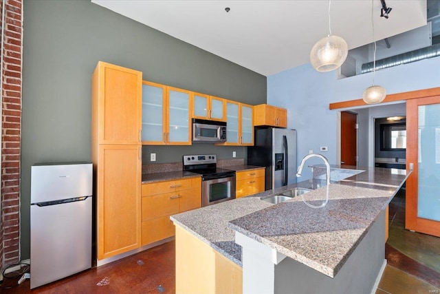 kitchen with stainless steel appliances, sink, a center island with sink, and light stone counters