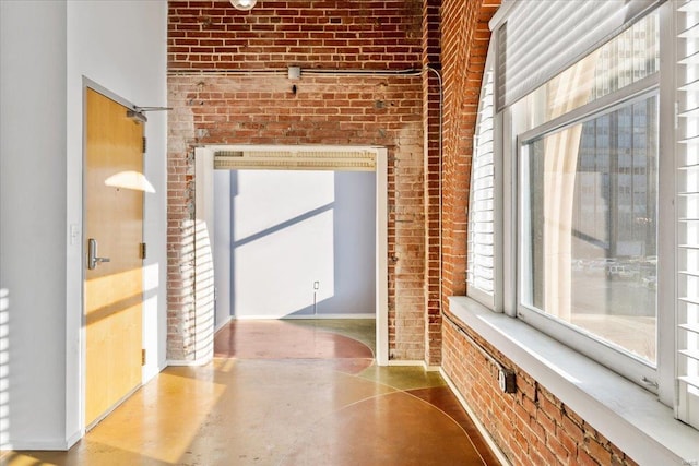 hallway featuring brick wall and concrete floors