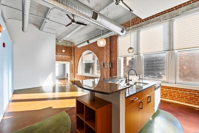 kitchen featuring a high ceiling, brick wall, sink, and a kitchen island with sink