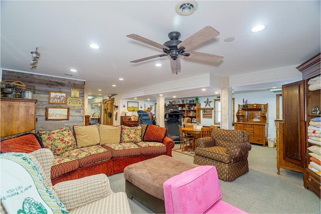 living room with decorative columns, ceiling fan, light colored carpet, and wooden walls