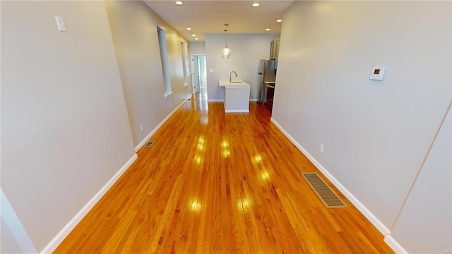 corridor featuring sink and light hardwood / wood-style flooring