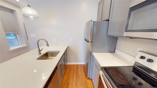 kitchen featuring sink, light hardwood / wood-style flooring, gray cabinets, electric range, and decorative light fixtures