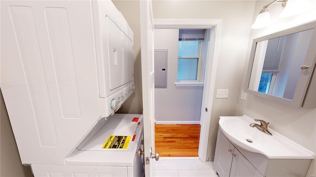 laundry room featuring light tile patterned floors, plenty of natural light, electric panel, and stacked washer / dryer