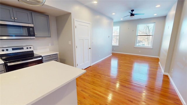 kitchen with ceiling fan, appliances with stainless steel finishes, light hardwood / wood-style flooring, and gray cabinetry