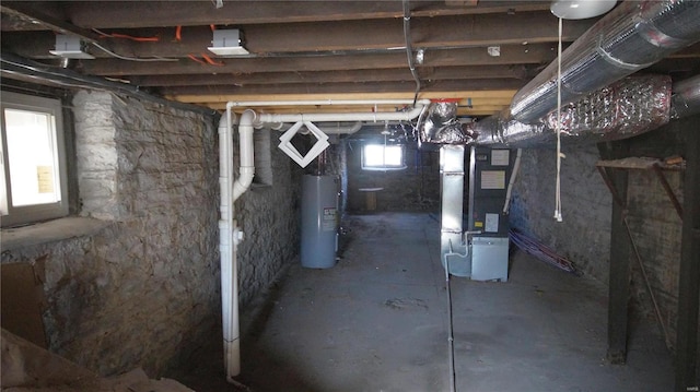 basement featuring heating unit, electric water heater, and a healthy amount of sunlight